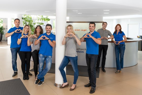 SWW Mitarbeiter im Kundencenter zeigen mit den Händen Herzsymbol