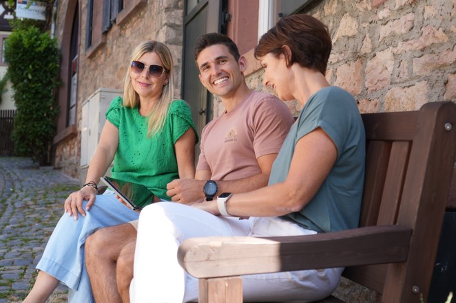 3 Menschen sitzen auf einer Holzbank